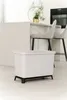 A modern kitchen setting with a trash bin in the foreground and a kitchen island with stools in the background. Náhľad obrázku produktu