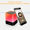 A Bluetooth speaker with a built-in clock and LED light, shown next to a smartphone displaying a music app. Produktbild-Vorschau