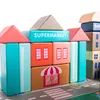 A collection of colorful wooden building blocks arranged to resemble a town with various buildings, including a supermarket. Anteprima dell’immagine prodotto