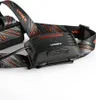 Close-up of a black headlamp with an orange and gray patterned strap. Podgląd zdjęcia produktu