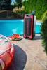 A JVC party speaker is placed on a tiled patio next to a swimming pool, with watermelon slices on a plate nearby. Anteprima dell’immagine prodotto