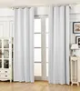 A room with white curtains covering a large window, a white cabinet on the left, and a small table with a lamp on the right. Produktbild-Vorschau