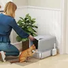 A woman is cleaning a cat litter box while a cat is inside. Produktbild-Vorschau