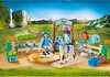 A Playmobil horse riding school playset with figures, horses, and accessories set against a scenic backdrop of waterfalls and green hills. Produktbild-Vorschau