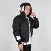 A young man wearing a black bomber jacket and a white t-shirt, posing against a light gray background.