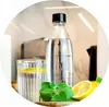 A SodaStream bottle and glass are on a counter with lemons and mint. Produktbild-Vorschau