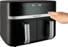 A hand is shown pressing a button on the digital display of a black dual-chamber air fryer. Produktbild-Vorschau