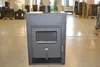 A dark gray wood-burning stove is displayed in the center of a room with a concrete floor. Other stoves and furniture are visible in the background. Produktbild-Vorschau