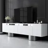 A modern white media console with metal cylinder legs is shown in a dark room. Voir les images du produit