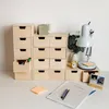 A desk setup with a wooden drawer unit, a desk lamp, and office supplies. Náhled obrázku produktu