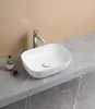 A white ceramic sink with a silver faucet is shown on a gray marble countertop, with a light beige wall in the background. Náhled obrázku produktu