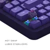 A close-up view of a purple mechanical keyboard with some keys removed to show the hot-swappable switches and lubed stabilizers. Produktbild-Vorschau
