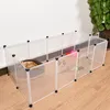 A white plastic pet enclosure with a white wire door, containing two cats and a pet bed, set up against a white wall on a wooden floor. Voir les images du produit