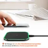 A hand is placing a smartphone on a wireless charger, with a newspaper and a cup in the background. Produktbild-Vorschau