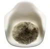 A round, fluffy sheepskin seat cushion is placed in the center of a white chair. Produktbild-Vorschau