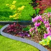 A garden bed with a decorative border, surrounded by grass and plants. Produktbild-Vorschau