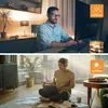 A split image showing two people working on laptops in different environments. The top image shows a man working at a desk in a dimly lit room, while the bottom image shows a woman working on the floor in a brightly lit living room. Voir les images du produit