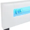 A close-up of a white upholstered bed frame with integrated LED lighting and a remote control. Náhled obrázku produktu