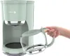 A hand is holding a glass coffee pot next to a green coffee maker. Produktbild-Vorschau