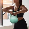 A woman is holding a kettlebell in a gym setting. Náhled obrázku produktu