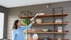A woman is vacuuming the ceiling with a cordless stick vacuum cleaner. Anteprima dell’immagine prodotto