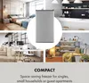 Collage showcasing a compact silver mini freezer in various settings, including a bedroom, office, and living room, with text emphasizing its compact nature. Náhled obrázku produktu