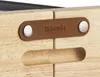 A close-up view of a wooden raclette grill with a leather brand tag. Voir les images du produit