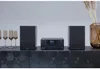 A stereo system with two speakers and a central unit is displayed on a dark, textured cabinet. There are also champagne glasses and a vase with dried flowers. Anteprima dell’immagine prodotto