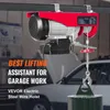 A red electric hoist is shown suspended from a beam in a garage setting, with a car visible in the background. Náhľad obrázku produktu