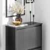 A close-up view of a black shoe cabinet with a decorative vase, a gold bowl, and two candles on top. Produktbild-Vorschau