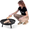 A woman is adding wood to a fire pit. Anteprima dell’immagine prodotto