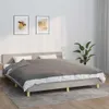 A bed with a gray duvet and white sheets, set against a white wall with two framed pictures and a potted plant. Náhled obrázku produktu