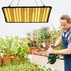 A man watering plants in a greenhouse under a grow light. Produktbild-Vorschau