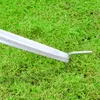 A close-up view of a white pole with a silver metal stake inserted into green grass. Anteprima dell’immagine prodotto