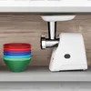A white meat grinder is shown on a shelf next to a stack of colorful bowls. Anteprima dell’immagine prodotto