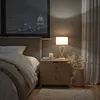 A bedroom scene at night with a city view through the window. Produktbild-Vorschau