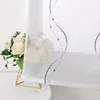 A close-up of a sheer curtain with a decorative embroidered pattern, next to a bouquet of white roses in a vase. Produktbild-Vorschau