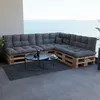 A sectional sofa made of wooden pallets with gray cushions is placed on a balcony overlooking the ocean. Anteprima dell’immagine prodotto