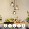 A dining table set with a fruit basket and bowls, under three pendant lights. Voir les images du produit