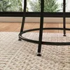 Close-up of the legs and base of a table on a rug, with a window and wooden floor in the background. Náhľad obrázku produktu