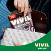 A hand is placing a VIVIL CremeLife Brasilitos Espresso candy packet into a purse. Produktbild-Vorschau