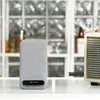 A wireless charger and a vintage-style speaker are placed on a white surface in front of a window with a blurred background. Produktbild-Vorschau