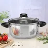 A stainless steel pot with a glass lid is placed on a table with some vegetables and spices. Produktbild-Vorschau