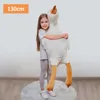 A young girl is hugging a large stuffed goose toy. Podgląd zdjęcia produktu