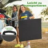 Two women are loading a folded table into the trunk of a car. Anteprima dell’immagine prodotto