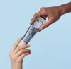 Two hands exchanging a tube of toothpaste. Anteprima dell’immagine prodotto