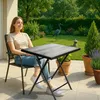 A woman sitting on a chair next to a square folding table on a patio. Produktbild-Vorschau