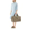 A woman stands holding a duffel bag. Voir les images du produit