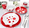 A collection of red and white polka dot dinnerware items arranged on a light wooden surface. Produktbild-Vorschau