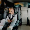 A young child is sitting in a car seat in the back seat of a car. Náhled obrázku produktu
